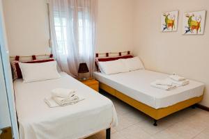 two beds in a room with white sheets and towels at Sunrise Horizon in Iraklitsa