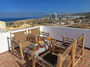 a balcony with a table and chairs on a roof at Dar Salam Asfi - Maison d'hôtes, terrasse vue Medina et océan in Safi