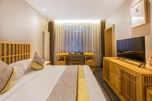 a bedroom with a large bed and a television at Mainland Chinese Only-Qinhuangdao Xinting Calligraphy Hotel in Qinhuangdao