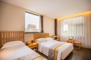 a hotel room with two beds and a window at Mainland Chinese Only-Qinhuangdao Xinting Calligraphy Hotel in Qinhuangdao