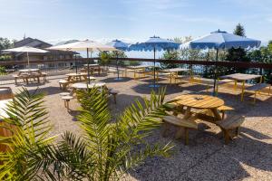 a patio with tables and chairs and umbrellas at Côté Lac Hostel Evian in Évian-les-Bains