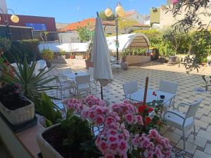 a patio with tables and chairs and an umbrella and flowers at Hotel Criniera D'oro in Rimini