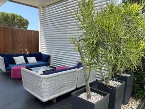 a patio with two potted trees and a wicker couch at Luxury Swimming Pool in Fontane Bianche