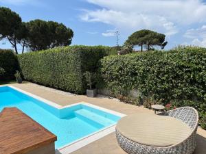 a swimming pool with a table and chairs next to a hedge at Luxury Swimming Pool in Fontane Bianche +45 photos
