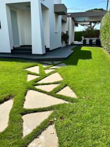 a grassy yard with a house with a walkway at Luxury Swimming Pool in Fontane Bianche