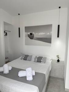 a white bedroom with a bed with white sheets and pillows at Fira Value Rooms- Fira Center- Capital Santorini in Fira