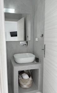 a bathroom with a white sink and a basket at Fira Value Rooms- Fira Center- Capital Santorini in Fira +15 photos