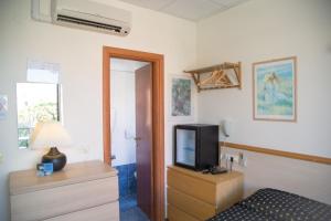 a room with a tv on a dresser with a bed at Hotel Delle Mimose in Diano Marina