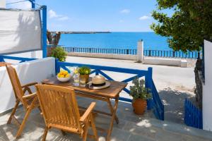a wooden table and chairs with a view of the ocean at Aegean Beachfront Suites in Andros