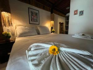 a white bed with a yellow flower on it at Pousada Tatuamar Café & Bistrô - 150 m da praia in Pôrto de Pedras