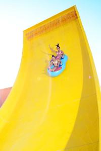 two people are riding a yellow water slide at Pickalbatros Jungle Aqua Park - Neverland Hurghada in Hurghada