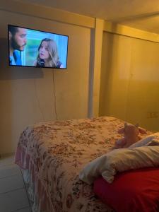 a bedroom with a bed with a tv on the wall at FLAT ZONA NORTE NATAL PRÓX PRAIA GENIPABU ou shopping partage in Natal