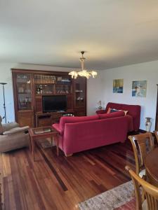 a living room with a red couch and a tv at Casa el Bosque in Camargo