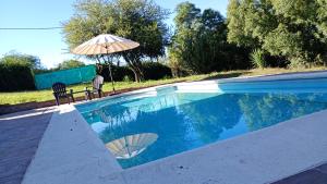 a swimming pool with an umbrella and a chair and a table at La Dominga Tiny House in La Granja
