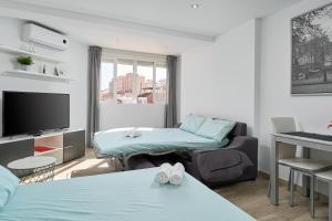 a living room with two beds and a tv at Estudio Plazamar Palace in Torre del Mar +19 photos