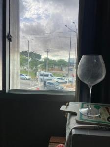 a wine glass sitting on a table next to a window at FLAT ZONA NORTE NATAL PRÓX PRAIA GENIPABU ou shopping partage in Natal