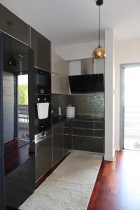 a kitchen with black cabinets and a large window at Vila 26, Lura 2, Gjiri i Lalezit in Ishëm