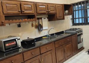 a kitchen with wooden cabinets and a sink and a microwave at Appartement de Deux chambres Salon à Ouando - SKYFORCE Bénin in Porto-Novo
