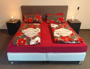 a bed with a red comforter and towels on it at Pension Malu die hundefreundliche Pension mit Frühstück ab 6 Uhr in Todenbüttel