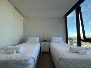 two twin beds in a room with a window at Southbank Sanctum in Melbourne +14 photos