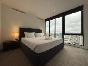 a bedroom with a large bed with a large window at Southbank Sanctum in Melbourne