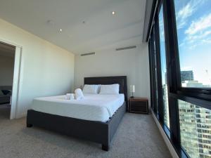 a bedroom with a bed and a large window at Southbank Sanctum in Melbourne