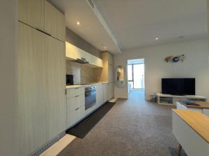a kitchen with white cabinets and a flat screen tv at Southbank Sanctum in Melbourne