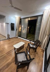 a living room with chairs and a table and a window at Kanakdhara farmhouse in Ujjain
