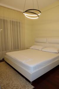 a white bed in a room with a chandelier at Vila 26, Lura 2, Gjiri i Lalezit in Ishëm