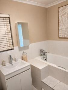 a white bathroom with a sink and a tub and a sink at The Olive Branch - Abbotsford in Dorchester Heights 