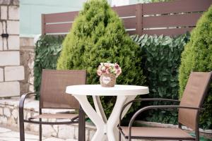 a white table with two chairs and a vase of flowers at Makis Apartments in Tsoukalades