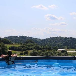 a woman in a swimming pool with a view at Hut at the forest, 1,5 hour from Bled in Male Brusnice