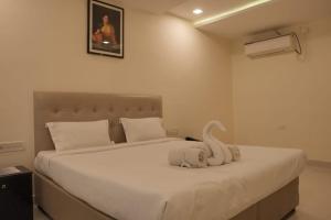 a bedroom with a bed with a stuffed animal on it at Hotel Surya Teja Priime in Khammam +4 photos