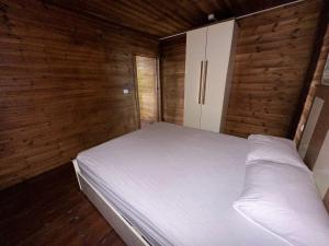 a bedroom with a white bed and wooden walls at carmel cabins suite 4 in ‘Isfiyā