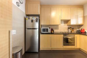 a kitchen with a stainless steel refrigerator and wooden cabinets at Comfy Central with Balcony and Views in Cape Town