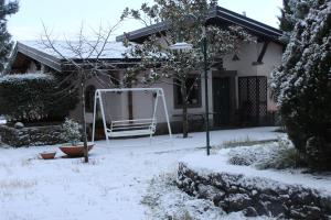 a snow covered yard with a swing in front of a house at La casa del Cavaliere in Santa Maria di Licodia