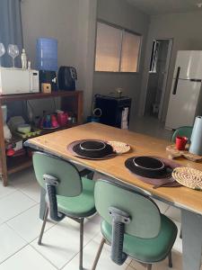 a wooden table with two green chairs and a kitchen at FLAT ZONA NORTE NATAL PRÓX PRAIA GENIPABU ou shopping partage in Natal
