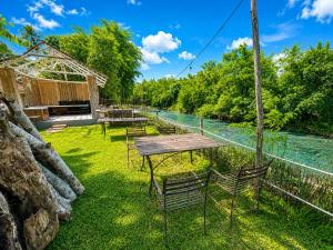 a picnic table and chairs next to a river at Ping Dara Pool Villa Party in Ban San Pa Sak