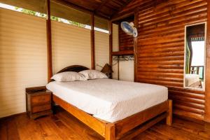 a bedroom with a bed in a wooden cabin at Cabañas Bella Vista in Hojancha
