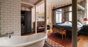 a bathroom with a tub and a bedroom with a bed at Hotel Kung Carl, WorldHotels Crafted in Stockholm