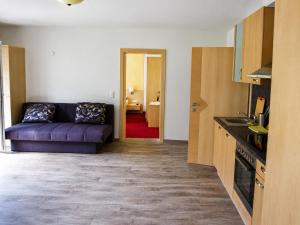 a living room with a purple couch and a kitchen at Appartement Tauernhof in Kleinarl