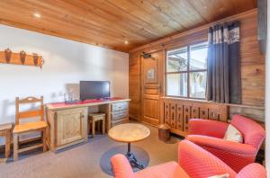 a living room with red chairs and a television at Hôtel Les Peupliers in Courchevel