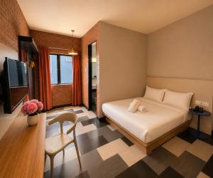 a bedroom with a bed and a chair and a television at the youniQ Hotel, KLIA T1, KLIA T2 in Sepang