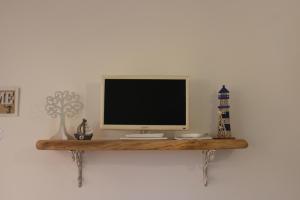 a television on a wooden shelf on a wall at Casa Briseida in Baia Verde