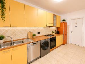 a kitchen with yellow cabinets and a sink and a dishwasher at Belvedere Apartment in Casa Donato