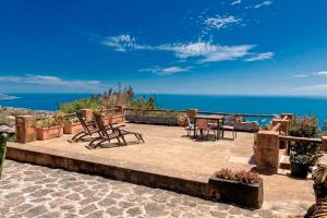 a patio with chairs and tables and the ocean at Celeste in Mazo