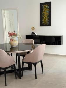 a dining room table with chairs and a vase with flowers at NYC trifft auf Top Moderne Wohnung in Hergla in Harqalah
