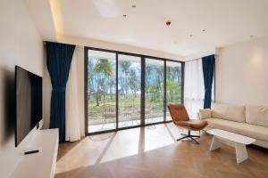a living room with a couch and a chair andwindows at Beachfront Luxury Apartment Bangtao Phuket in Bang Tao Beach