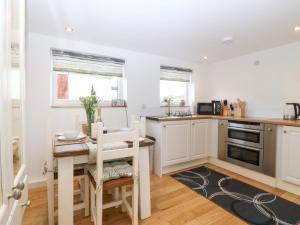 a kitchen with white cabinets and a small table and chairs at Ty Loti in Caernarfon