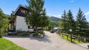 a house with a car parked next to a driveway at Hostdomus - La Tana della Volpe in Sauze d'Oulx
